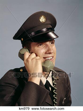 Stock Photo - 1960s smiling young man soldier wearing army uniform talking on telephone. Fotosearch