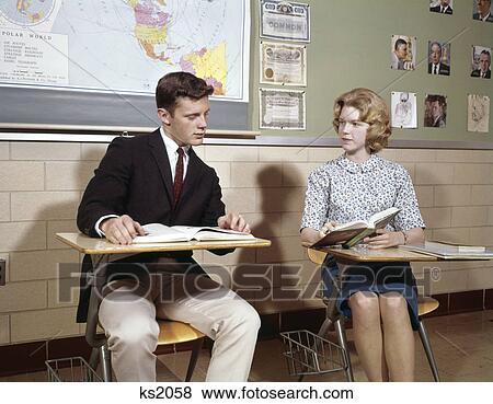 1960s teenage boy girl seated classroom desks talking View Large Photo Image Stock Photo - 1960s teenage boy girl seated classroom desks talking. Fotosearch