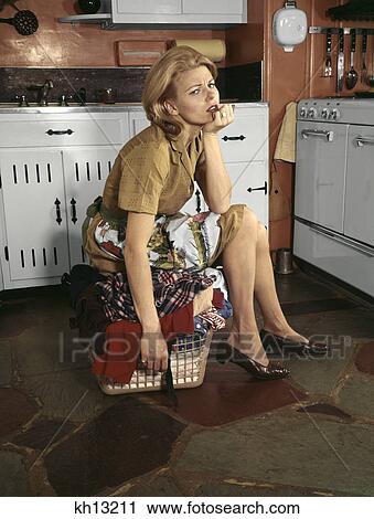 1960s tired housewife sitting on top of laundry basket in kitchen View Large Photo Image Stock Image - 1960s tired housewife sitting on top of laundry basket in kitchen. Fotosearch