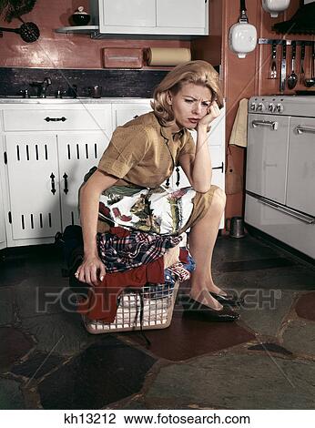1960s tired housewife sitting on top of laundry basket in kitchen View Large Photo Image Stock Image - 1960s tired housewife sitting on top of laundry basket in kitchen. Fotosearch