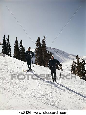 Stock Photograph - 1960s two men skiers on winter slope colorado. Fotosearch