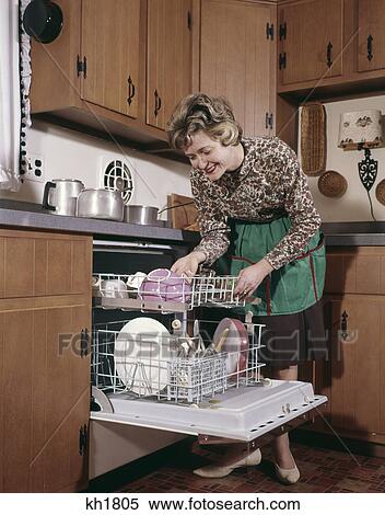 Stock Photography - 1960s woman apron dishwasher housework kitchen. Fotosearch