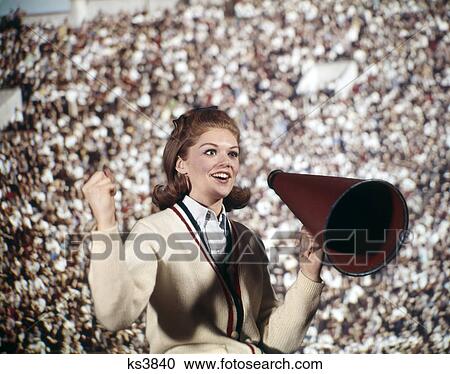 Stock Image - 1960s woman girl cheerleader cheering red megaphone sweater crowd. Fotosearch
