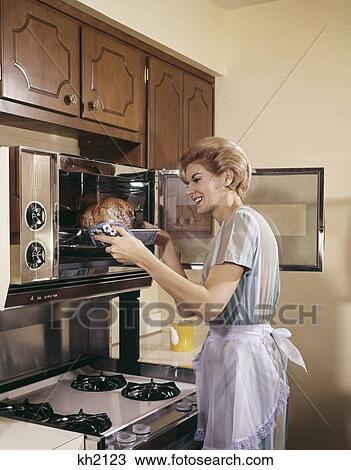 1960s woman housewife in apron oven baking cooking poultry in kitchen View Large Photo Image Stock Image - 1960s woman housewife in apron oven baking cooking poultry in kitchen. Fotosearch