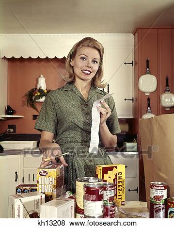 1960s young blond housewife smiling while checking grocery shopping receipt in kitchen View Large Photo Image Stock Photo - 1960s young blond housewife smiling while checking grocery shopping receipt in kitchen. Fotosearch