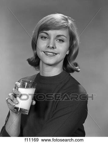 Stock Photo - 1960s young smiling woman holding a glass of milk. Fotosearch
