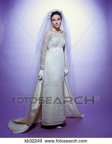 1960s young woman bride portrait bridal veil empire waist gown lace bodice hem full length View Large Photo Image Stock Photo - 1960s young woman bride portrait bridal veil empire waist gown lace bodice hem full length. Fotosearch