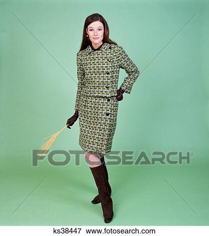 Stock Photo - 1960s young woman modeling green wool knit two piece suit fishnet stockings boots full length clothe. Fotosearch