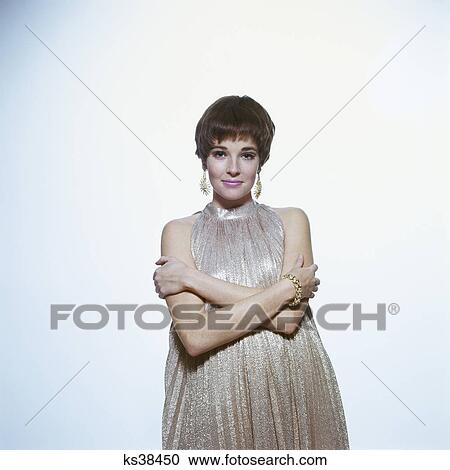1960s young woman wear pleated metallic dress pixie hair style arms folded earrings bracelet View Large Photo Image Stock Image - 1960s young woman wear pleated metallic dress pixie hair style arms folded earrings bracelet. Fotosearch