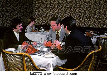 Stock Image - 1970s 3 businessmen at table in restaurant. Fotosearch