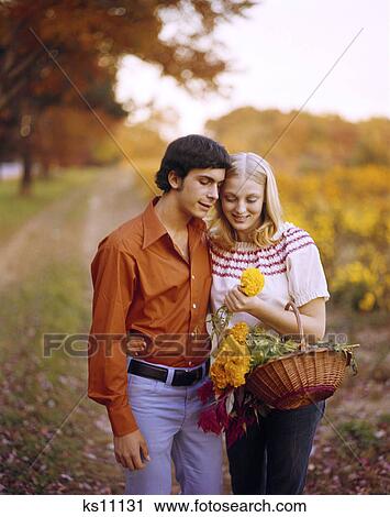 1970s affectionate young couple with basket of flowers on country road autumn romantic man woman View Large Photo Image Stock Image - 1970s affectionate young couple with basket of flowers on country road autumn romantic man woman. Fotosearch