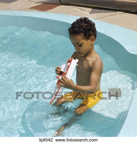 1970s african american boy playing with toy boat in backyard swimming pool View Large Photo Image Stock Image - 1970s african american boy playing with toy boat in backyard swimming pool. Fotosearch