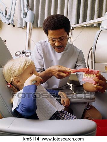 1970s african-american dentist teaching young caucasian girl proper tooth brushing method View Large Photo Image Picture - 1970s african-american dentist teaching young caucasian girl proper tooth brushing method. Fotosearch