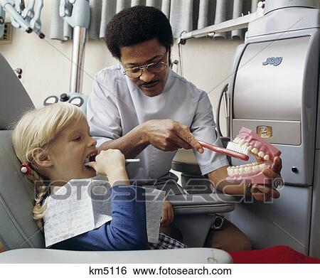 Stock Photograph - 1970s african american dentist teaching child how to brush teeth. Fotosearch
