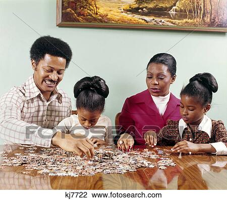 1970s african american family man woman mother father two children girls sitting at table doing jigsaw puzzle View Large Photo Image Stock Image - 1970s african american family man woman mother father two children girls sitting at table doing jigsaw puzzle. Fotosearch