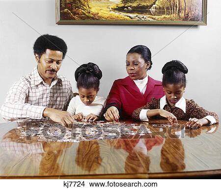 1970s african american family sitting at table doing jigsaw puzzle View Large Photo Image Picture - 1970s african american family sitting at table doing jigsaw puzzle. Fotosearch