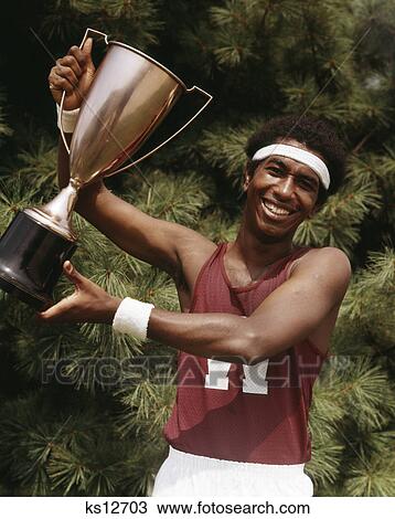 1970s african american young man athlete holding track & field trophy View Large Photo Image Stock Image - 1970s african american young man athlete holding track & field trophy. Fotosearch