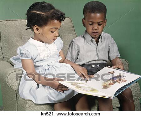 Stock Image - 1970s children reading boy girl. Fotosearch