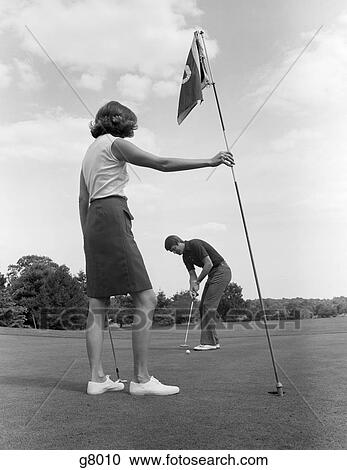 Stock Image - 1970s couple green put putting. Fotosearch