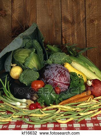 Stock Image - 1970s display of fresh garden vegetables on red checkered tablecloth. Fotosearch