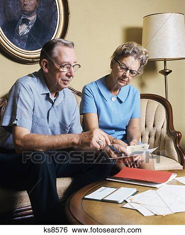 1970s elderly couple coffee table reviewing mail bills paperwork View Large Photo Image Stock Photograph - 1970s elderly couple coffee table reviewing mail bills paperwork. Fotosearch