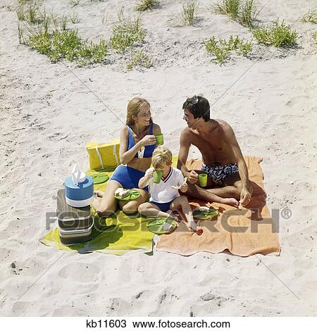Stock Image - 1970s family having picnic on beach ocean city new jersey usa. Fotosearch