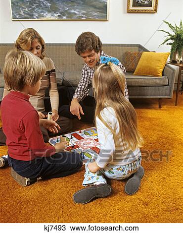 1970s family playing board game in living room sitting on floor with shag carpet View Large Photo Image Stock Image - 1970s family playing board game in living room sitting on floor with shag carpet. Fotosearch