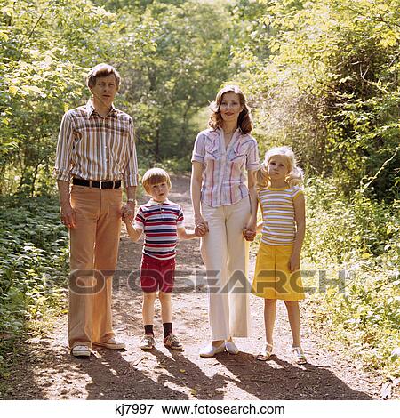1970s family walking outdoors full length mother father two kids man woman boy girl summer View Large Photo Image Stock Photo - 1970s family walking outdoors full length mother father two kids man woman boy girl summer. Fotosearch