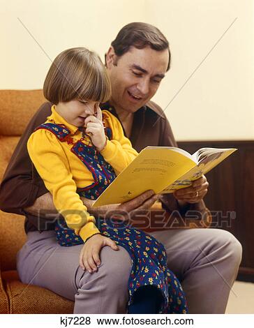 1970s father reading book to daughter sitting on his lap View Large Photo Image Stock Photo - 1970s father reading book to daughter sitting on his lap. Fotosearch