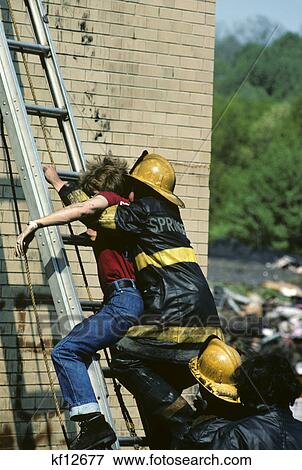 Stock Photo - 1970s firefighter and victim ladder during fire rescue training. Fotosearch