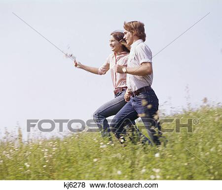 1970s happy teenaged couple running in field of wildflowers holding hands View Large Photo Image Stock Photo - 1970s happy teenaged couple running in field of wildflowers holding hands. Fotosearch
