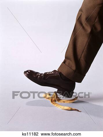 Stock Image - 1970s male foot about to step on banana peel. Fotosearch
