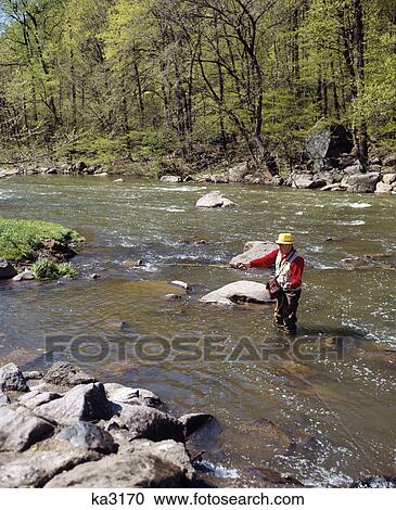 1970s man fly fishing in stream wearing rubber waders View Large Photo Image Stock Image - 1970s man fly fishing in stream wearing rubber waders. Fotosearch