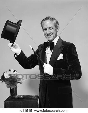 1970s man magician wearing velvet tuxedo white gloves pointing wand to top hat in hand View Large Photo Image Stock Photography - 1970s man magician wearing velvet tuxedo white gloves pointing wand to top hat in hand. Fotosearch