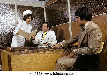 Stock Photo - 1970s man patient meeting in doctors office nurse woman showing folder to male doctor. Fotosearch