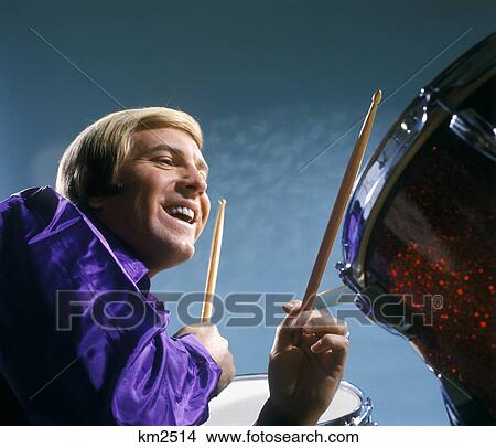1970s man playing drums wearing purple shirt View Large Photo Image Picture - 1970s man playing drums wearing purple shirt. Fotosearch
