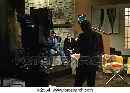 Picture - 1970s men in front of camera television news studio. Fotosearch