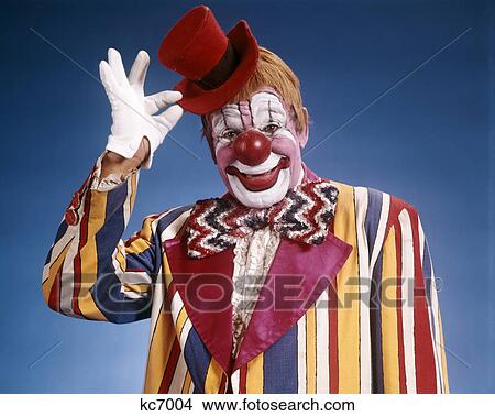 1970s portrait of clown in striped costume tipping little red top hat View Large Photo Image Picture - 1970s portrait of clown in striped costume tipping little red top hat. Fotosearch