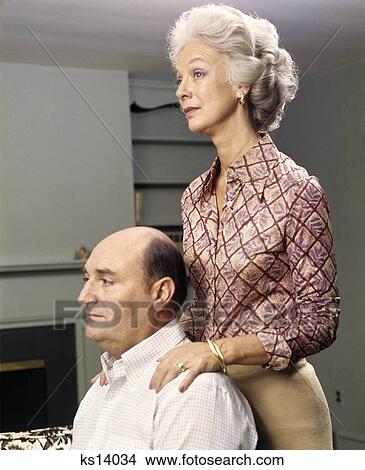 1970s profile portrait of serious senior couple man sitting woman standing View Large Photo Image Picture - 1970s profile portrait of serious senior couple man sitting woman standing. Fotosearch