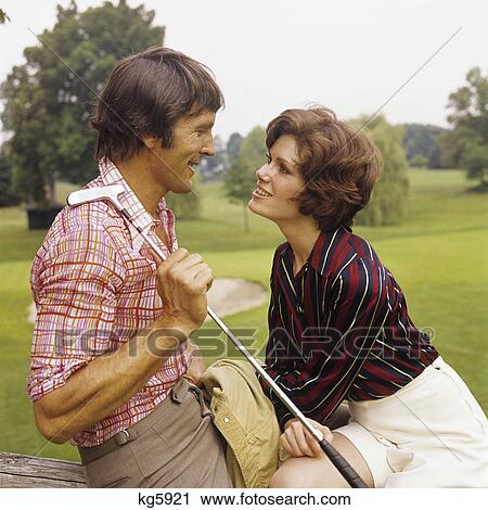 Stock Image - 1970s romantic couple man woman golf course. Fotosearch