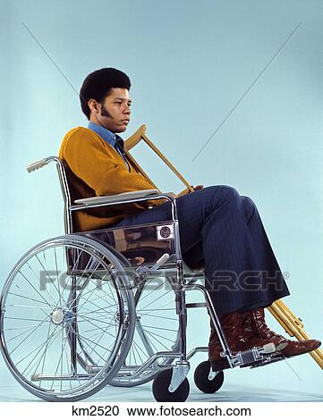1970s sad african american man sitting in wheelchair holding crutches View Large Photo Image Stock Image - 1970s sad african american man sitting in wheelchair holding crutches. Fotosearch