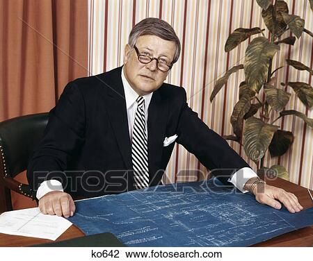 1970s serious businessman at desk with blueprints View Large Photo Image Stock Image - 1970s serious businessman at desk with blueprints. Fotosearch