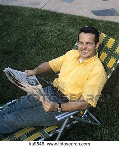 1970s smiling man sitting in lawn chair reading newspaper relaxing leisure outdoors View Large Photo Image Stock Photograph - 1970s smiling man sitting in lawn chair reading newspaper relaxing leisure outdoors. Fotosearch