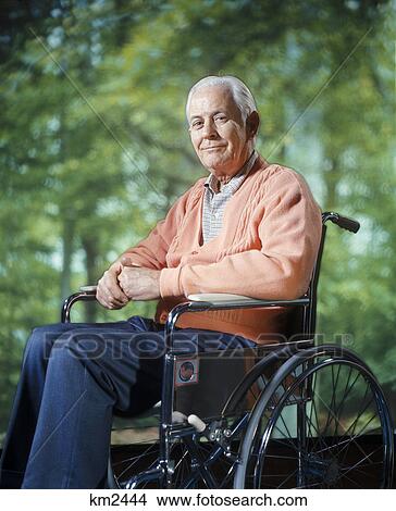 Picture - 1970s smiling senior man sitting in wheelchair outdoors. Fotosearch