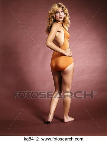 1970s smiling woman wearing orange bathing suit looking over her shoulder View Large Photo Image Stock Image - 1970s smiling woman wearing orange bathing suit looking over her shoulder. Fotosearch
