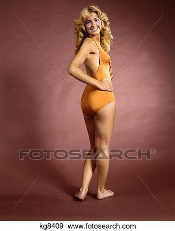 1970s smiling woman wearing orange bathing suit looking over her shoulder View Large Photo Image Stock Photo - 1970s smiling woman wearing orange bathing suit looking over her shoulder. Fotosearch