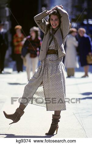 1970s stylish young woman smiling holding hands over head wearing beige outfit View Large Photo Image Picture - 1970s stylish young woman smiling holding hands over head wearing beige outfit. Fotosearch
