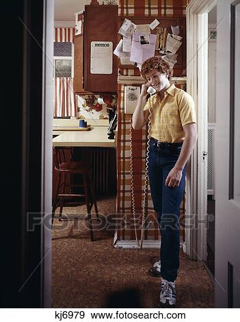 1970s teenage boy talking on kitchen wall phone telephone View Large Photo Image Stock Photo - 1970s teenage boy talking on kitchen wall phone telephone. Fotosearch