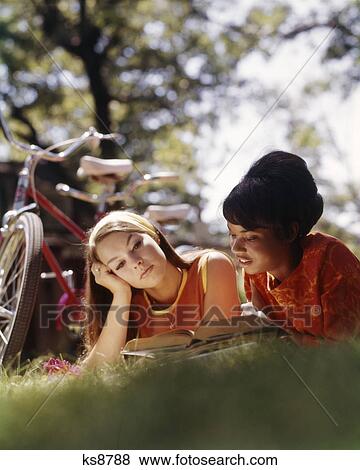1970s two college woman students laying on grass with books studying one african american one caucasian View Large Photo Image Stock Photo - 1970s two college woman students laying on grass with books studying one african american one caucasian. Fotosearch