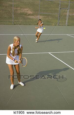 Stock Photography - 1970s two teen girls playing doubles tennis. Fotosearch